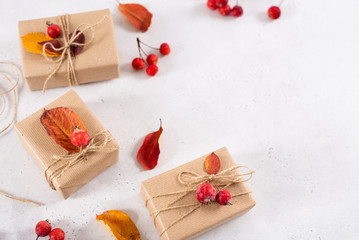 Autumn vibes, thanksgiving day presents, seasonal sale concept. Fall composition with presents in craft paper decorated with dried leaves on white background. Copy space, top view