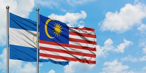Nicaragua and Malaysia flag waving in the wind against white cloudy blue sky together. Diplomacy concept, international relations.