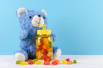 vitamins for children like jelly candy and teddy bear on blue background