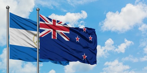 Nicaragua and New Zealand flag waving in the wind against white cloudy blue sky together. Diplomacy...
