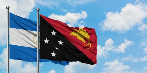 Nicaragua and Papua New Guinea flag waving in the wind against white cloudy blue sky together. Diplomacy concept, international relations.