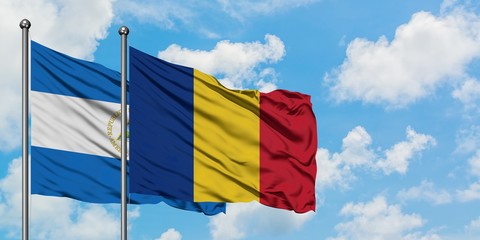 Nicaragua and Romania flag waving in the wind against white cloudy blue sky together. Diplomacy concept, international relations.