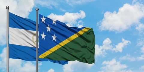 Nicaragua and Solomon Islands flag waving in the wind against white cloudy blue sky together....
