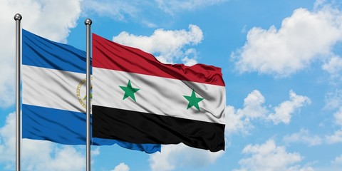 Nicaragua and Syria flag waving in the wind against white cloudy blue sky together. Diplomacy...