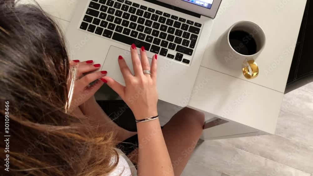 Poster the girl sits at a table and writes on a black keyboard laptops. view of top to down