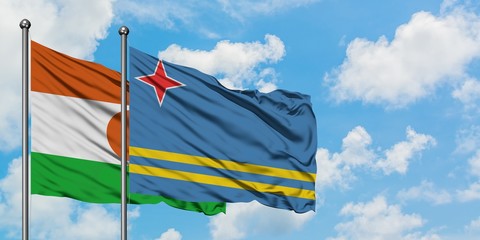 Niger and Aruba flag waving in the wind against white cloudy blue sky together. Diplomacy concept, international relations.