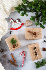 Christmas composition. Christmas gifts, knitted blanket, pine cones, fir branches on concrete gray background. Flat lay, top view