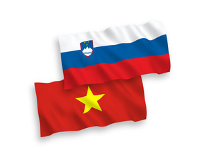 National vector fabric wave flags of Slovenia and Vietnam isolated on white background. 1 to 2 proportion.