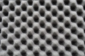 Dark artificial foam, acoustic foam insulation texture on background.