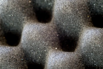 Dark artificial foam, acoustic foam insulation texture on background.