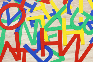 colorful jumbled letters, made of paper,  lying on wood