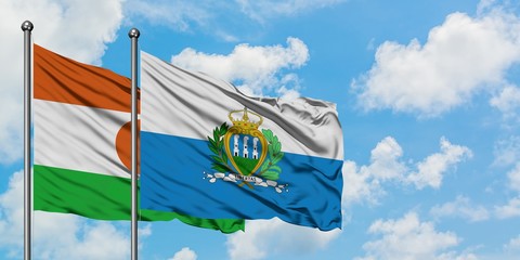 Niger and San Marino flag waving in the wind against white cloudy blue sky together. Diplomacy...