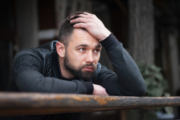 Pensive bearded young man outdoors in the afternoon in the city.