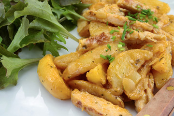 fried potatoes and chicken with salad on a plate