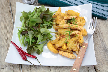 fried potatoes and chicken with salad on a plate