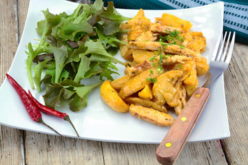 fried potatoes and chicken with salad on a plate