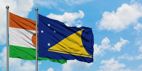 Niger and Tokelau flag waving in the wind against white cloudy blue sky together. Diplomacy concept, international relations.