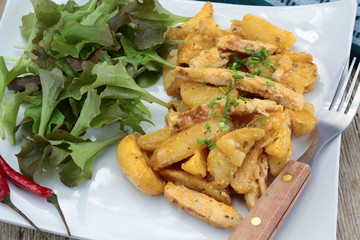 fried potatoes and chicken with salad on a plate