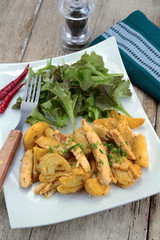 fried potatoes and chicken with salad on a plate