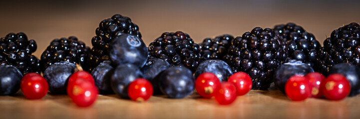 Panorama, fresh local fruits on wooden table, blackberries, blueberries and redcurrants