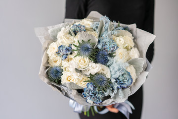 White and blue color. Beautiful bouquet of mixed flowers in womans hands. the work of the florist at a flower shop. Fresh cut flower.