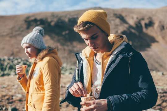 Teen guy drinking tea or coffee in mountains with friends