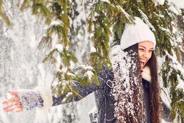 Girl under falling snow from a tree in the park in winter.