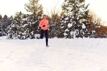 Girl jogging in the snow on the nature in winter