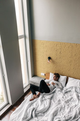 Young man relaxing on comfy bed in modern hotel room