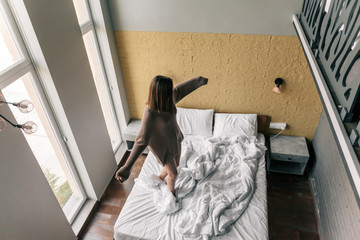 Young girl relaxing on comfy bed in modern hotel room