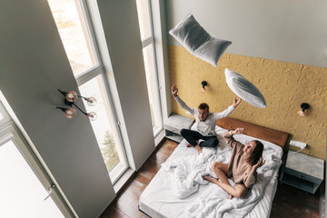 Young girl and guy relaxing on comfy bed in modern hotel room