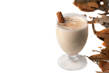 Eggnog Christmas cocktail in a transparent wine glass, decorated with cinnamon stick, sprinkled with grated nutmeg. Isolated on white background. Copy space.