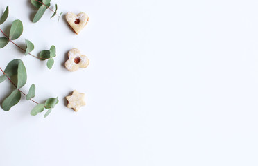New Year or Christmas background with eucalyptus and homemade festive sweets. Party decoration. Flat lay, top view.