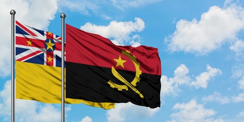 Niue and Angola flag waving in the wind against white cloudy blue sky together. Diplomacy concept,...