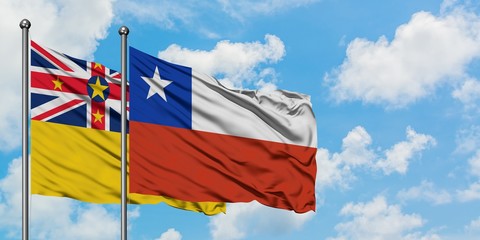 Niue and Chile flag waving in the wind against white cloudy blue sky together. Diplomacy concept, international relations.