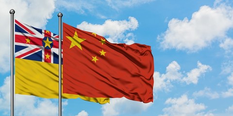 Niue and China flag waving in the wind against white cloudy blue sky together. Diplomacy concept,...
