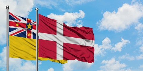 Niue and Denmark flag waving in the wind against white cloudy blue sky together. Diplomacy concept, international relations.