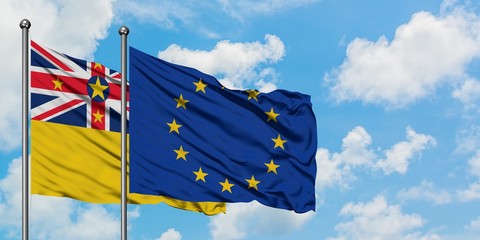 Niue and European Union flag waving in the wind against white cloudy blue sky together. Diplomacy concept, international relations.