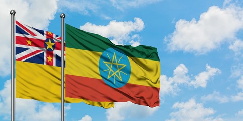 Niue and Ethiopia flag waving in the wind against white cloudy blue sky together. Diplomacy concept, international relations.