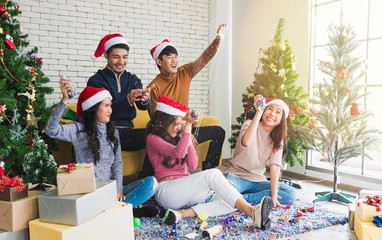 Group of young smile people in winter season playing and feel funny from color string spray for celebrate in Christmas party