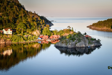 Fototapeta na wymiar sunlight is shining on the red coastal houses of the Norwegian coast
