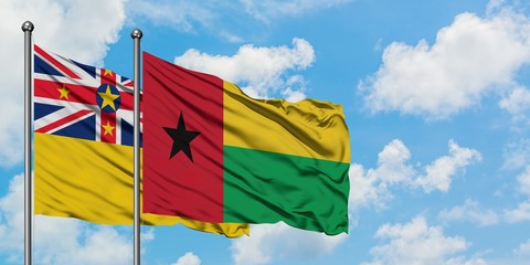 Niue and Guinea Bissau flag waving in the wind against white cloudy blue sky together. Diplomacy concept, international relations.