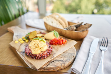 Roasted octopus BBQ with Baked potato. Wooden plate. Restaurant menu