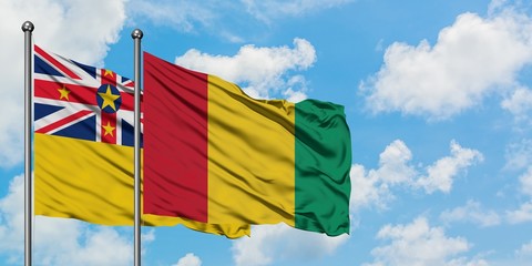 Niue and Guinea flag waving in the wind against white cloudy blue sky together. Diplomacy concept, international relations.