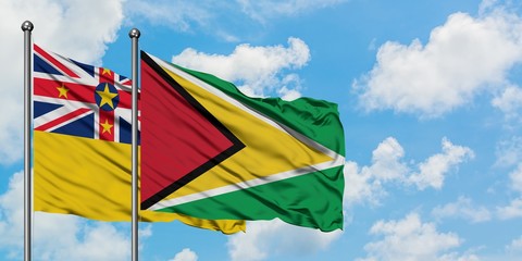 Niue and Guyana flag waving in the wind against white cloudy blue sky together. Diplomacy concept, international relations.