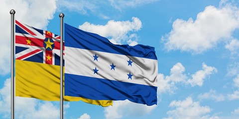 Niue and Honduras flag waving in the wind against white cloudy blue sky together. Diplomacy...