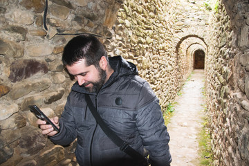 Man looks at his smartphone in a stone tunnel with a smile