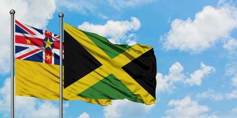 Niue and Jamaica flag waving in the wind against white cloudy blue sky together. Diplomacy concept, international relations.