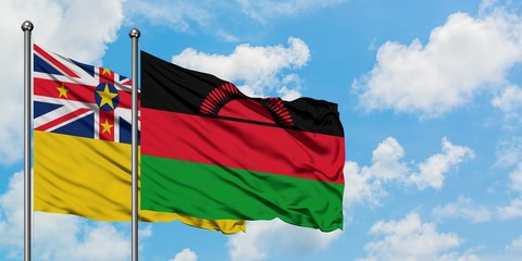 Niue and Malawi flag waving in the wind against white cloudy blue sky together. Diplomacy concept, international relations.