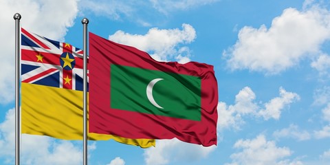 Niue and Maldives flag waving in the wind against white cloudy blue sky together. Diplomacy...
